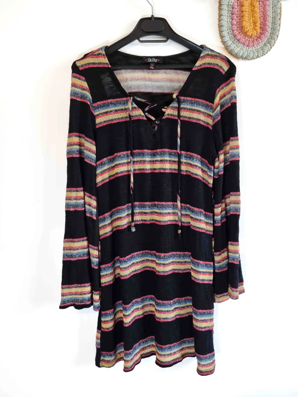 Vestido de manga larga a rayas multicolor con escote en V y cordones. La tela es tejida y liviana.