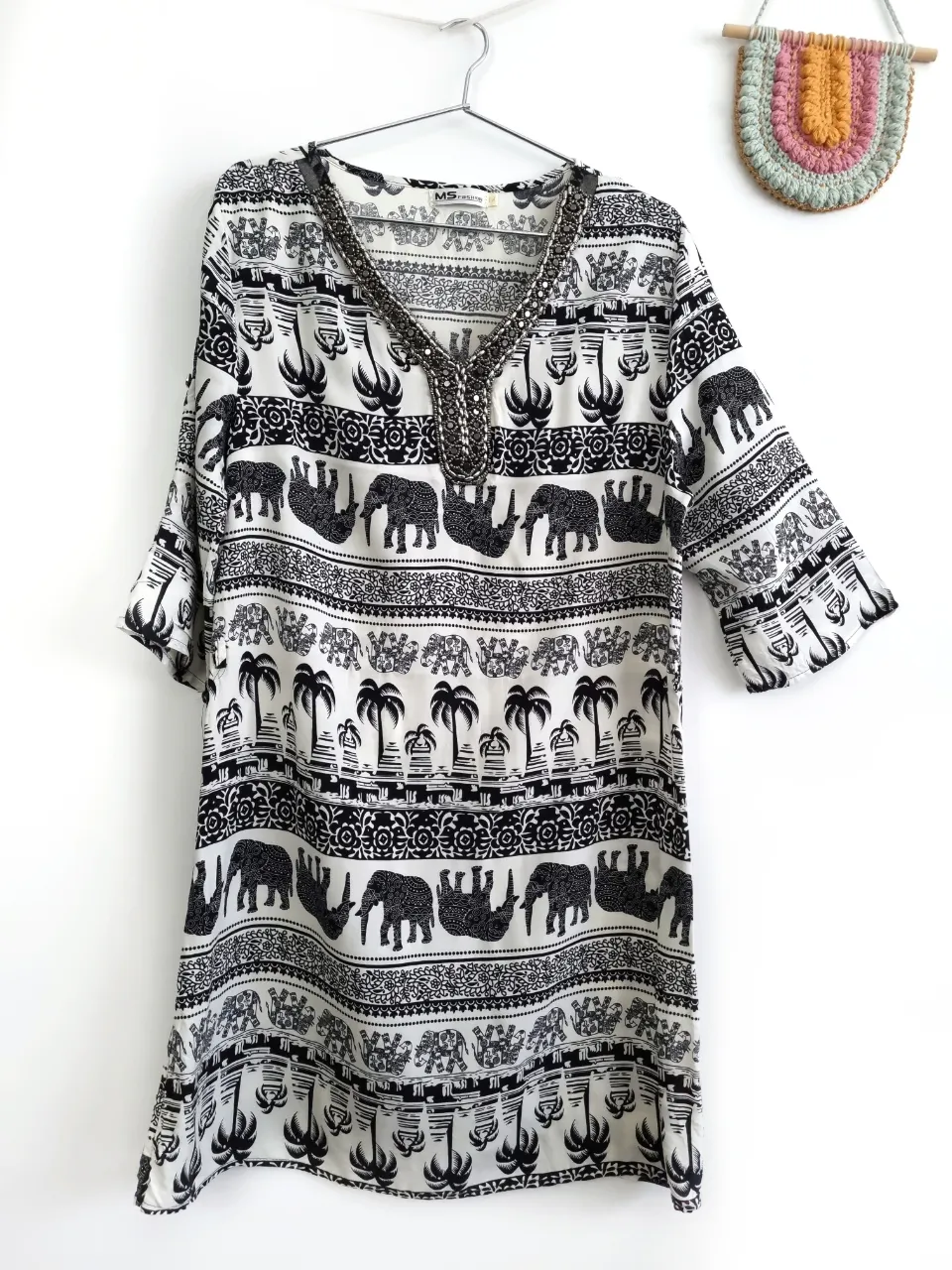 Vestido blanco y negro con estampa de elefantes y palmeras. Posee detalles de pedrería en el cuello.