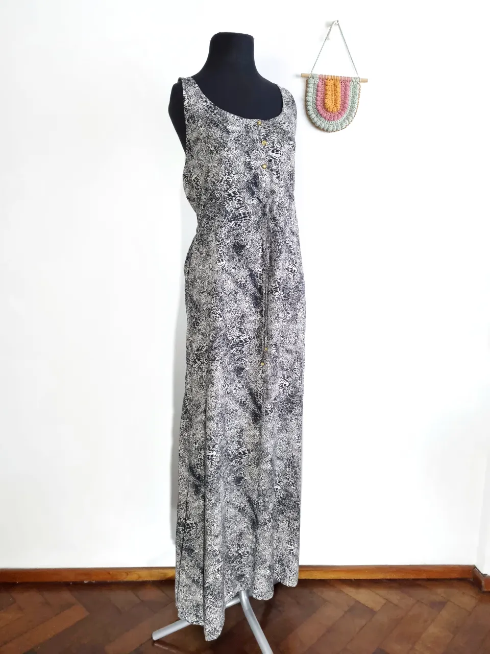 Vestido largo estampado en blanco y negro, sin mangas, con botones dorados en la parte delantera y un lazo en la cintura.