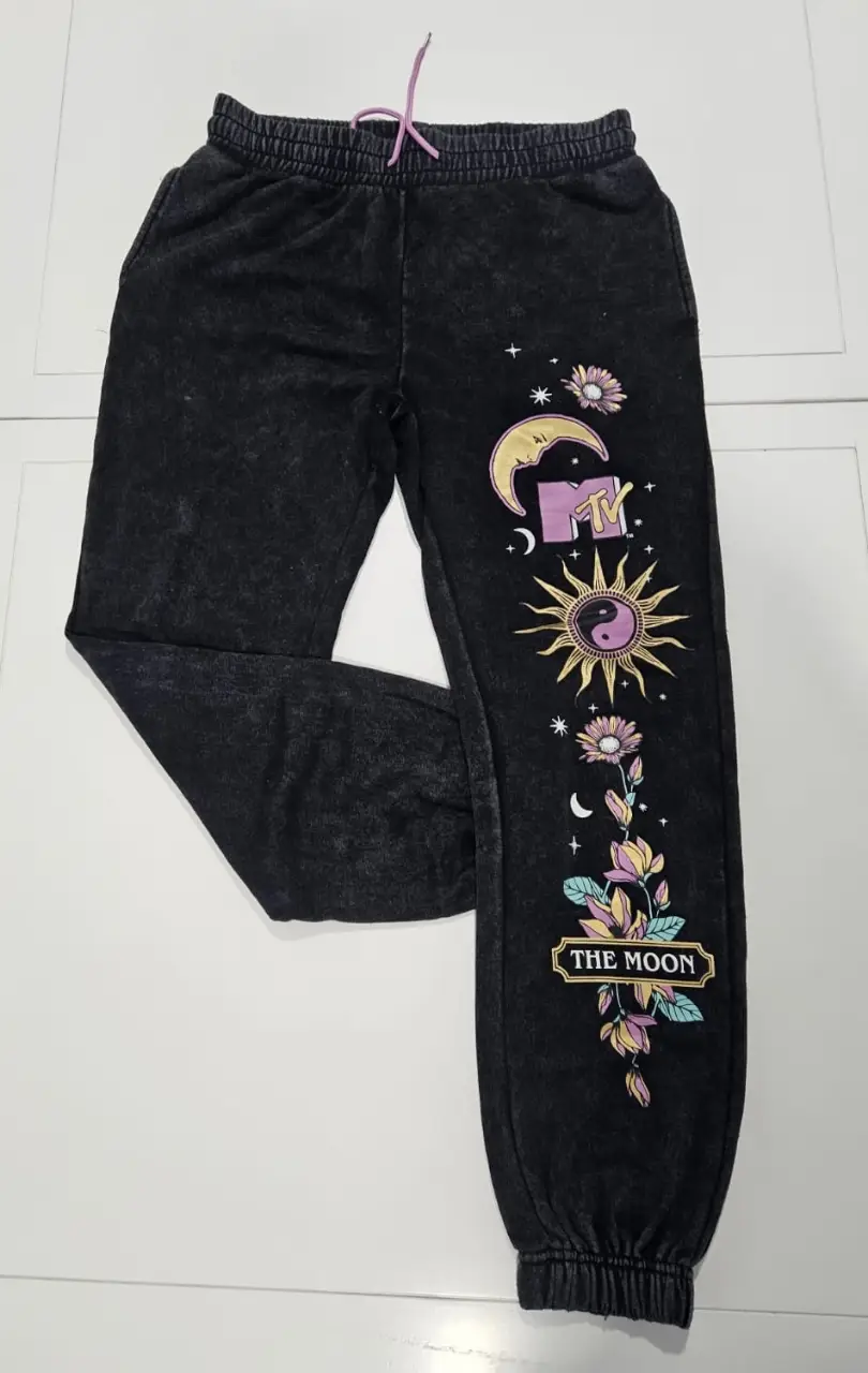 Pantalón de jogging negro con estampado de diseño gráfico en la pierna. Estilo vintage con logo MTV y detalles florales. Ideal para un look casual y cómodo.