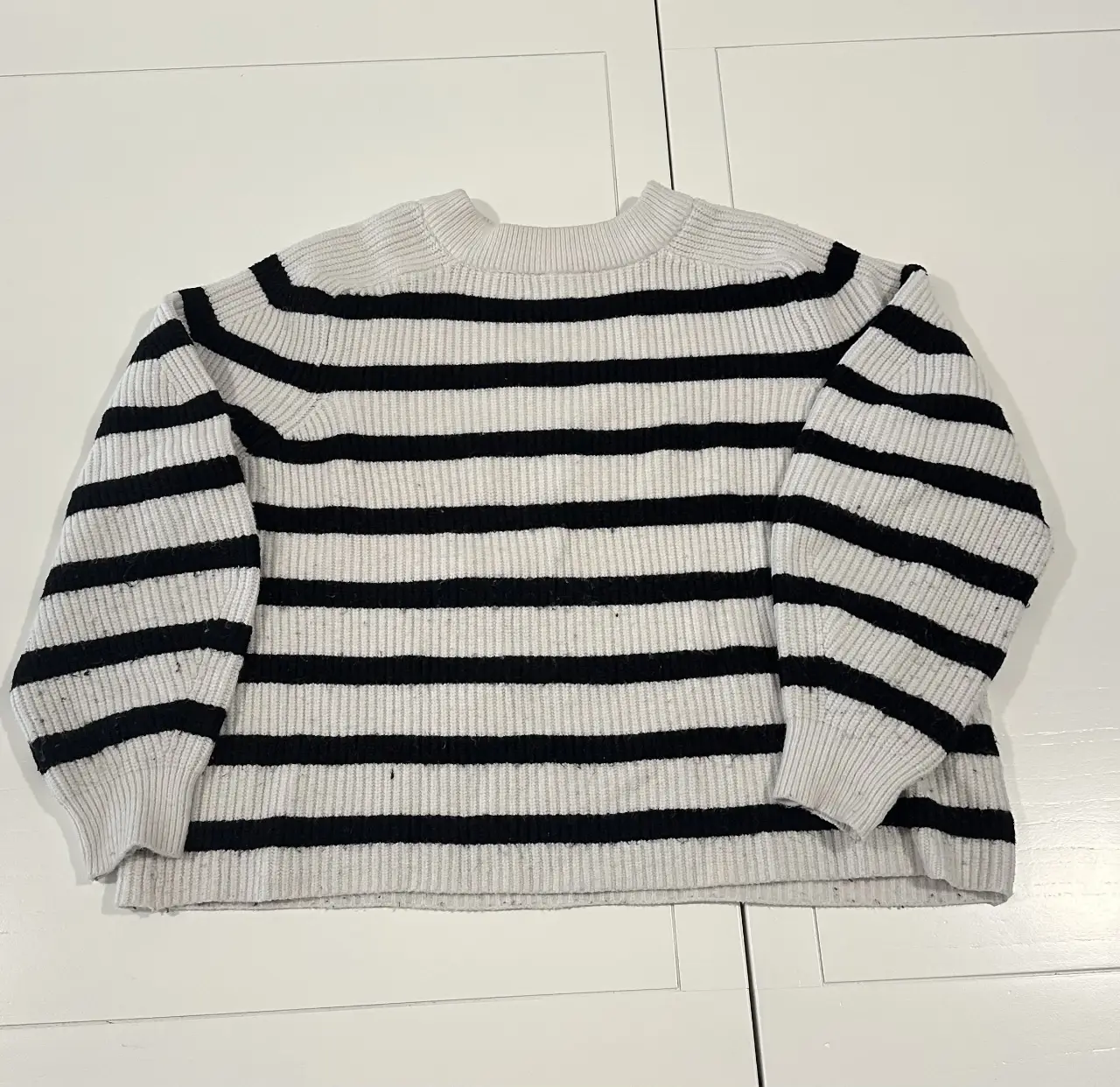 Sweater de cuello alto a rayas horizontales en blanco y negro, ideal para un look casual y moderno. Perfecto para combinar con jeans o pantalones de vestir.