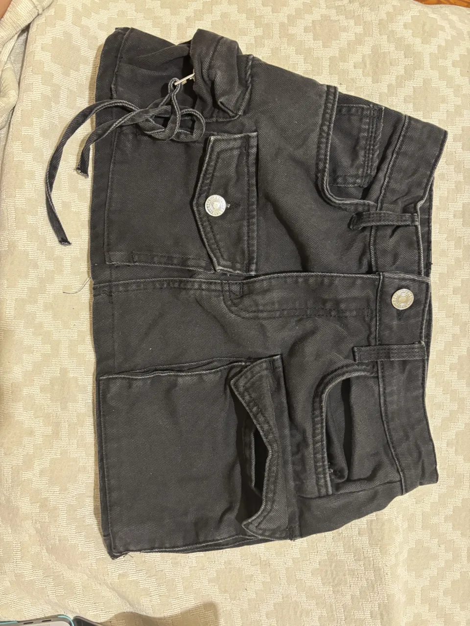 Pollera de jean negros con bolsillos cargo y cordón en la cintura.