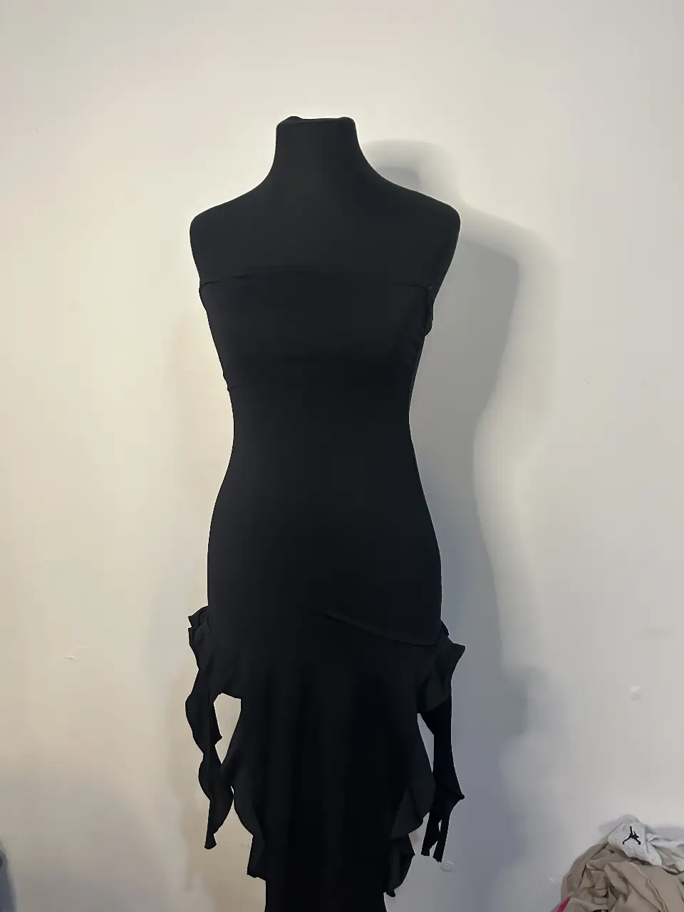 Vestido negro mini strapless con detalle de volados en la parte inferior. Ideal para una fiesta o salida nocturna.