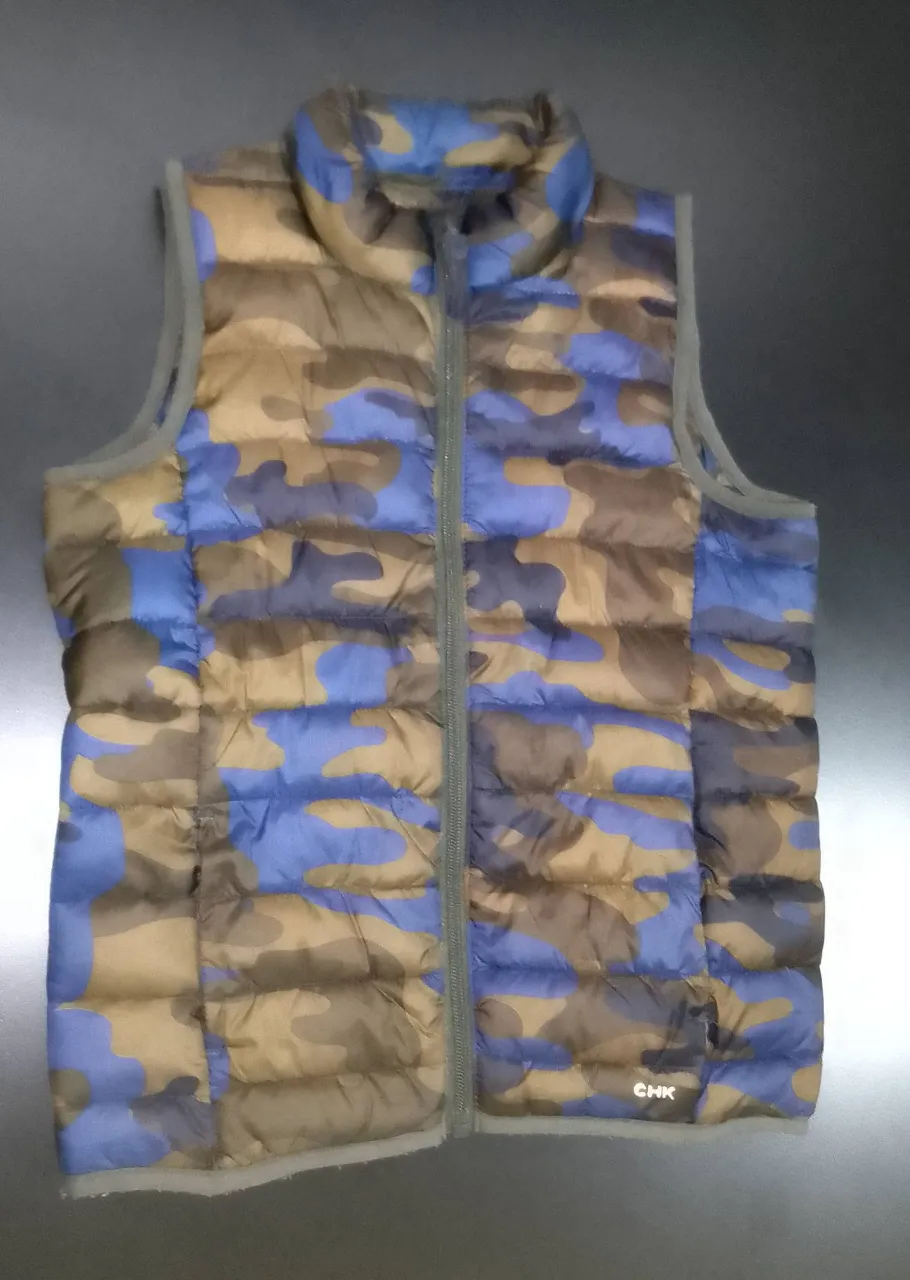 Chaleco acolchado para niño con estampado de camuflaje en tonos azul y marrón. Ideal para  media estación, este chaleco sin mangas es perfecto para un look casual y abrigado.