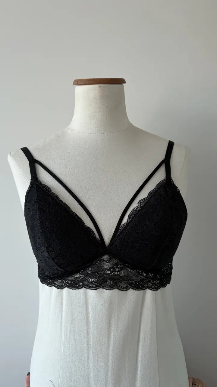 Corpiño de encaje negro con tiras finas y detalle de puntilla en el borde. Ideal para usar como prenda interior o como parte de un look más audaz.