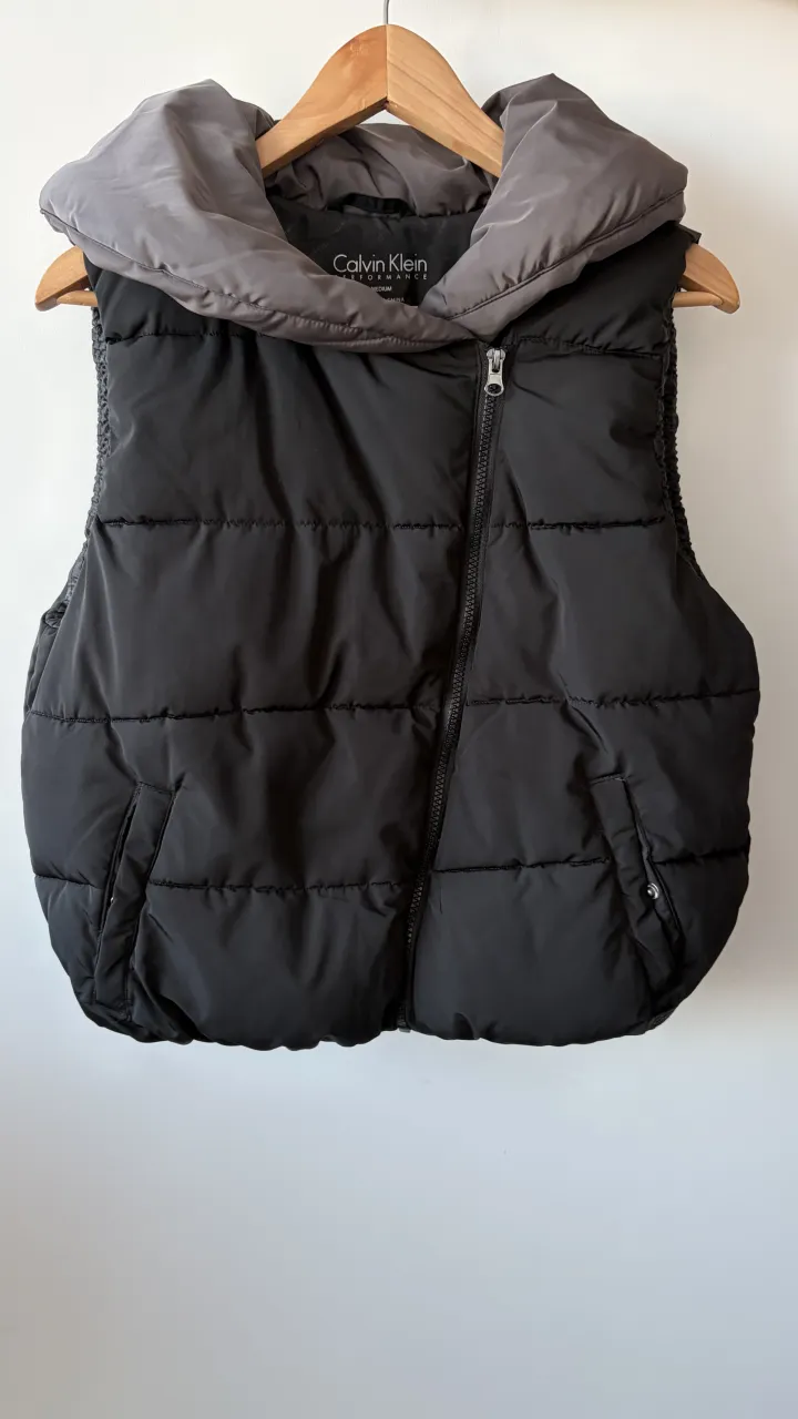 Chaleco acolchado negro con cuello alto gris. Ideal para un look casual y abrigado en días frescos. Posee cierre al frente y bolsillos laterales. UN SOLO USO
