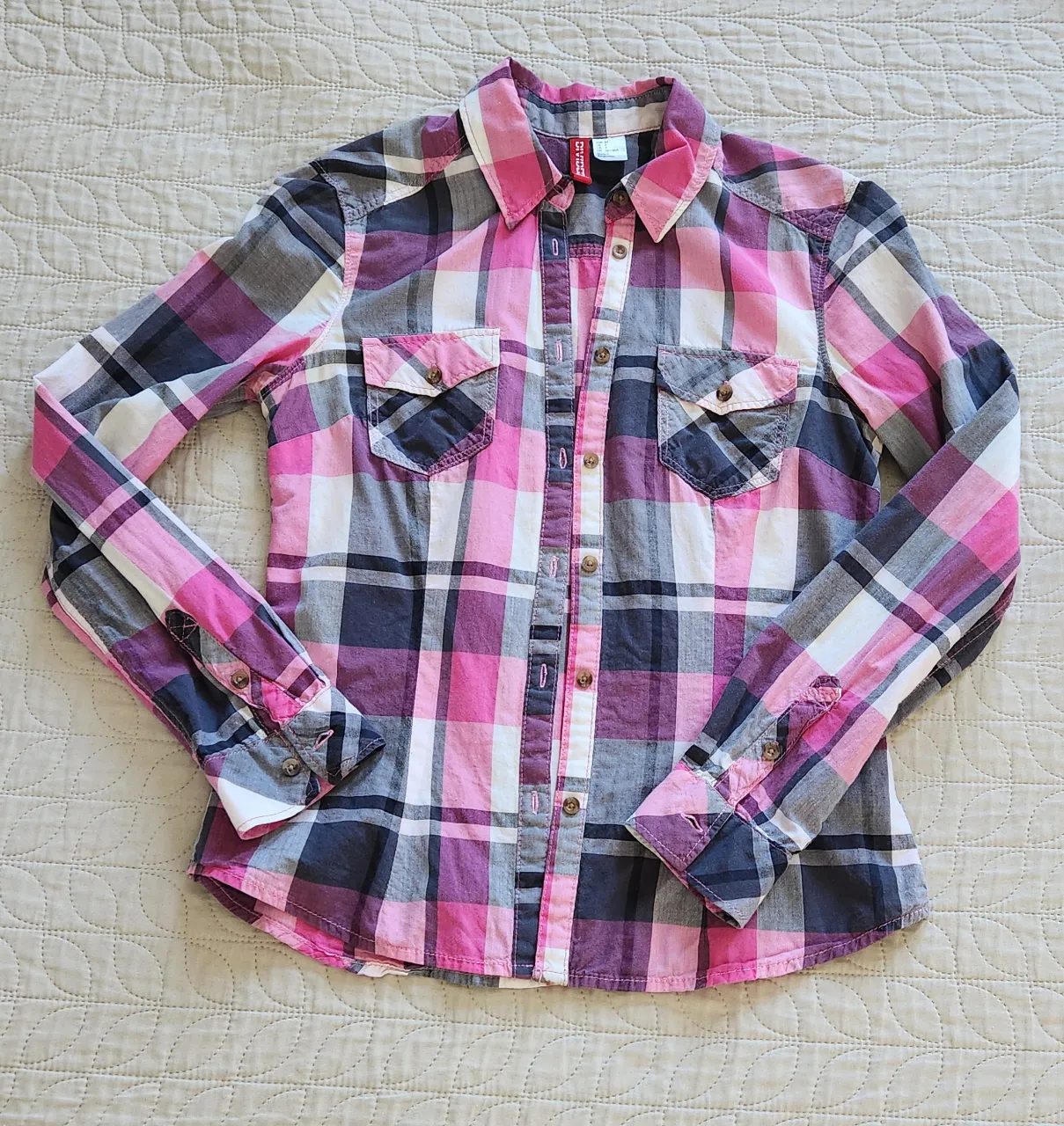 Camisa a cuadros de manga larga con botones al frente y dos bolsillos en el pecho. Los puños tienen botones.