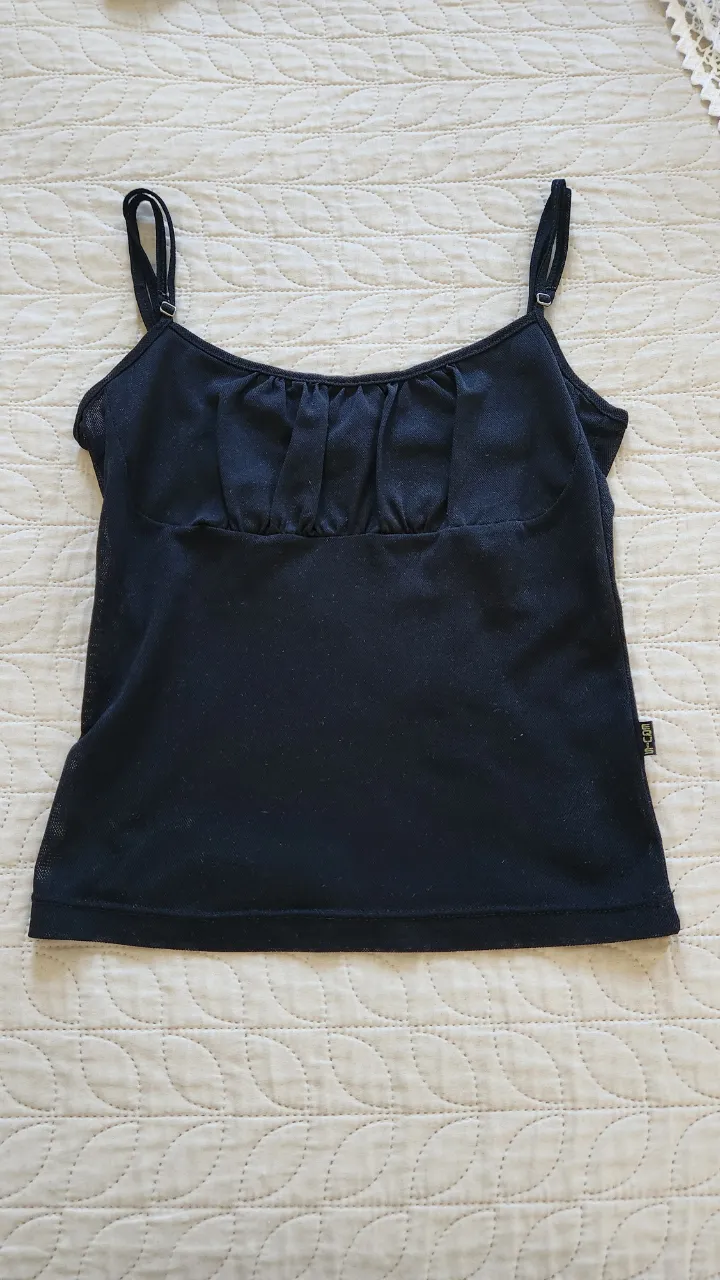 Musculosa negra con tiras finas regulables y detalle fruncido en el busto.