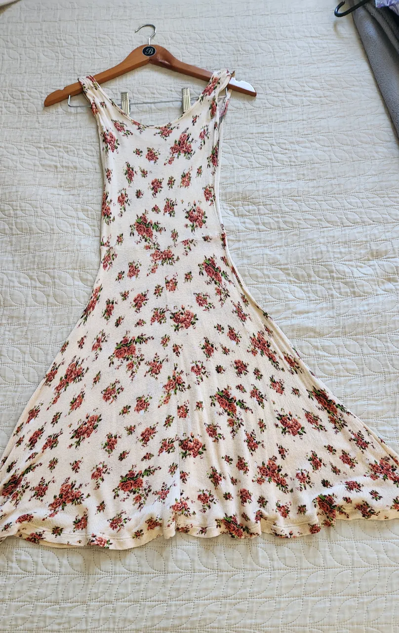 Vestido corto estampado con flores pequeñas en tonos rojos y verdes sobre fondo crudo. Breteles finos y falda con movimiento.