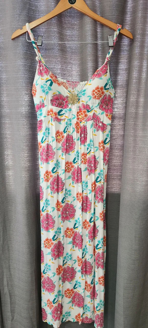 Vestido largo blanco con estampa floral multicolor. Posee breteles finos y detalle de bordado en la zona del busto.