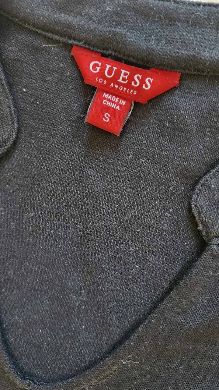 Remera negra de manga corta con cuello en V y un bolsillo en el pecho izquierdo. Presenta un pequeño bordado de la marca en el bolsillo.