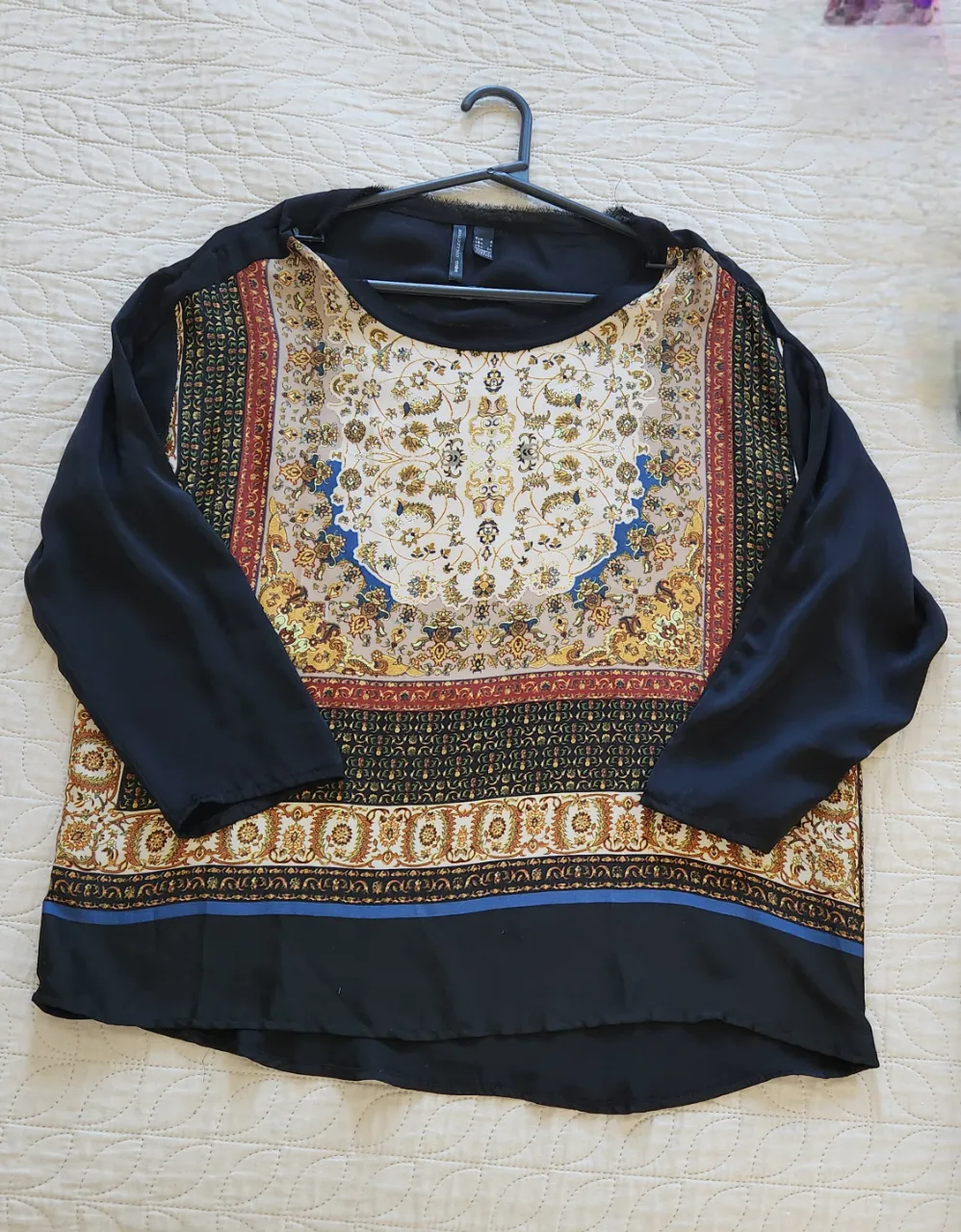 Remera manga larga con estampa floral y geométrica en el frente. Fondo negro en mangas y parte inferior.