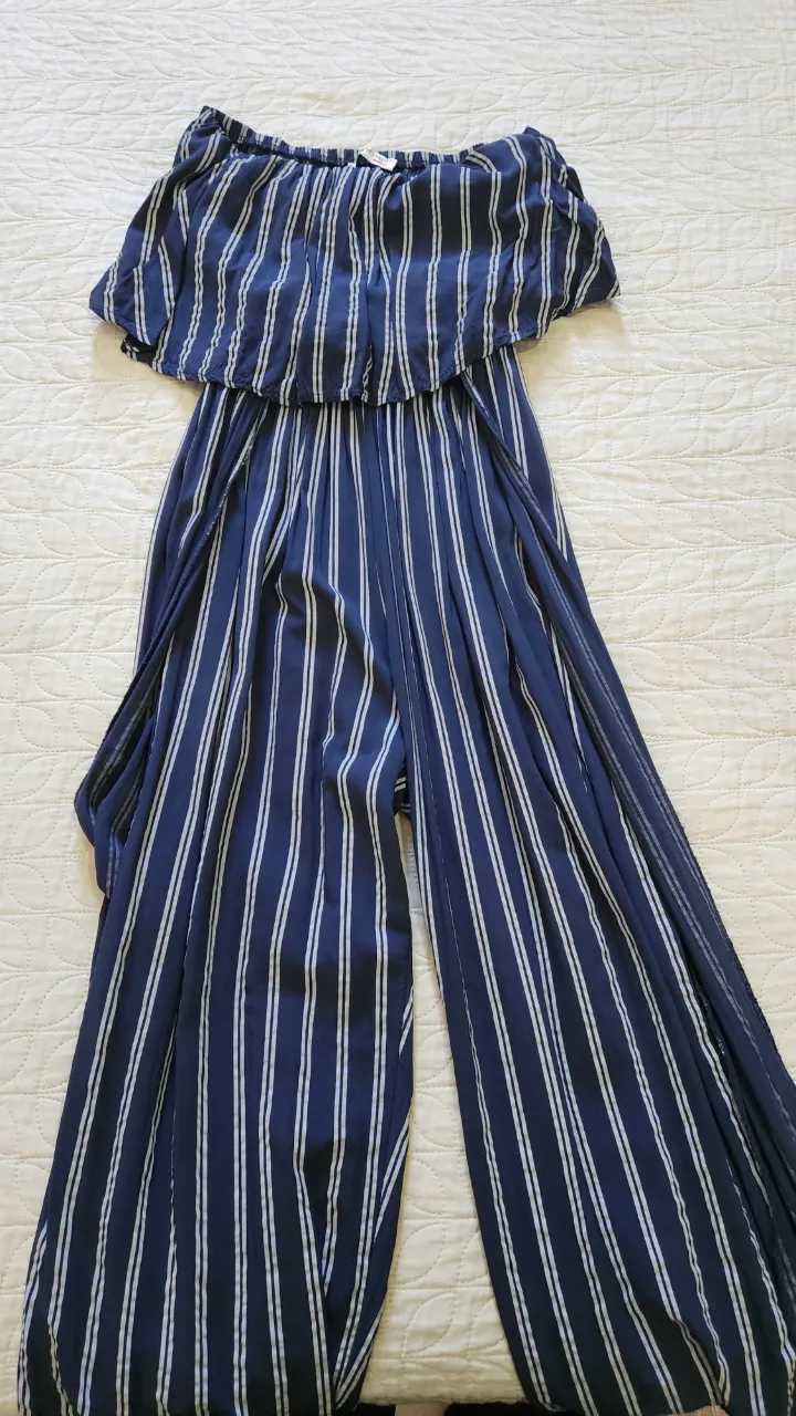 Mono de vestir a rayas verticales, con escote strapless y volado. Piernas anchas y sueltas con tajos a los costados.Fabricado en Italia.