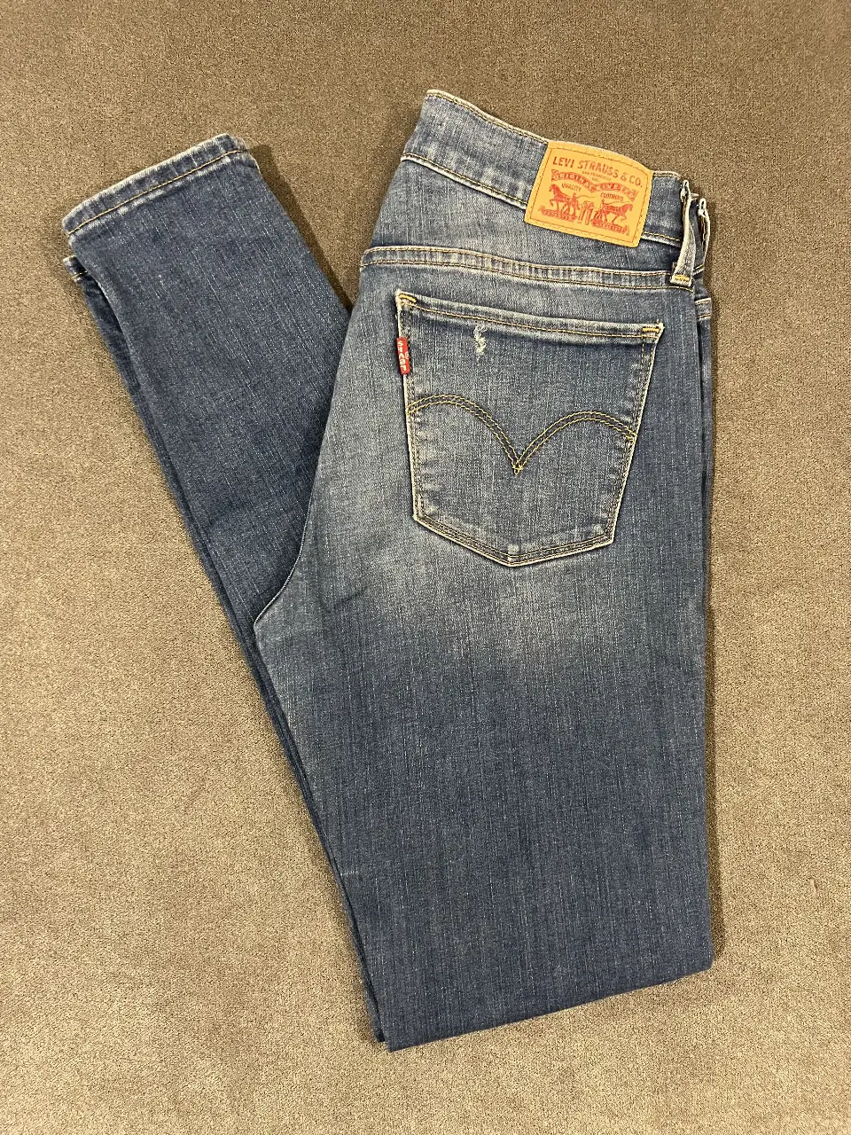 Jeans Levi's azul clásico, corte Chupin, con detalles de desgaste y el icónico parche de la marca. Un básico atemporal para cualquier guardarropa.