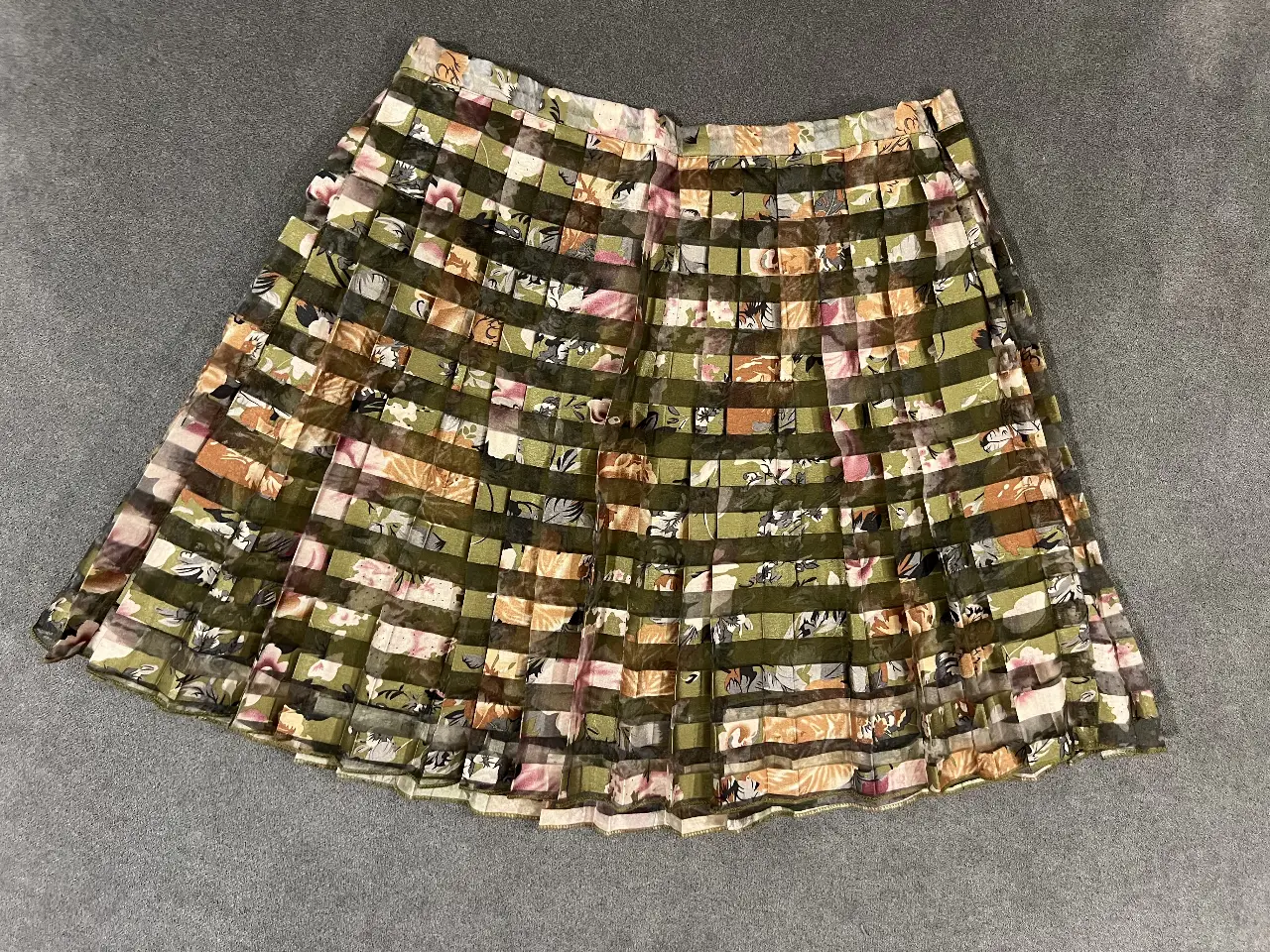 Pollera larga pero antes de las rodillas con diseño floral y a cuadros en tonos verdes y beige. Ideal para un look bohemio y fresco.