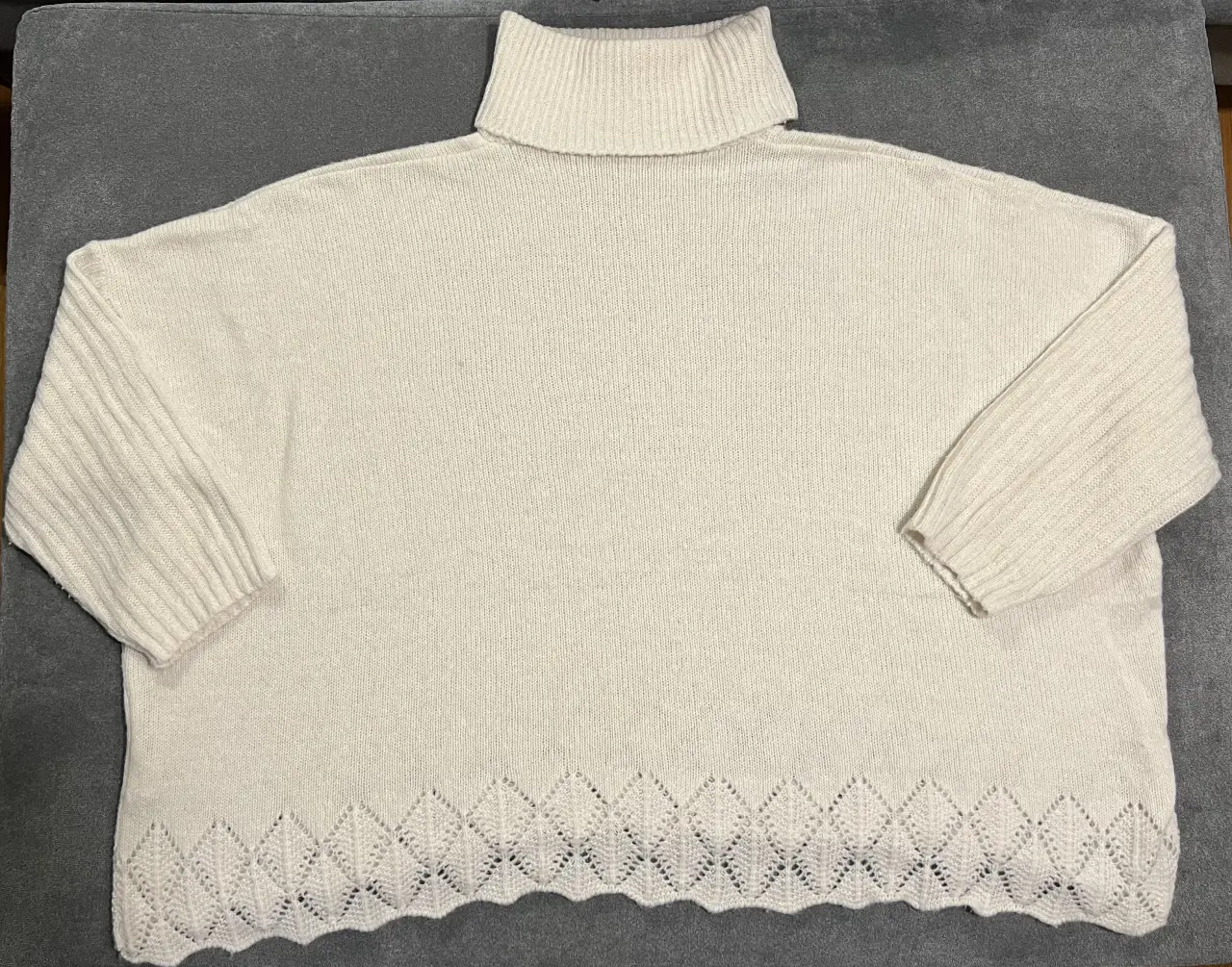 Sweater de cuello alto en color crudo, con detalle calado en el borde inferior. Ideal para un look casual y abrigado.