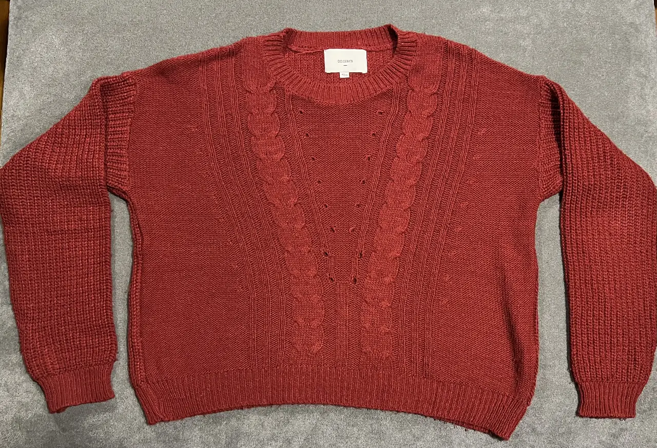 Sweater de tejido  color rojo  con detalles trenzados en el frente. Cuello redondo y mangas largas con puños. Ideal para un look casual y abrigado.