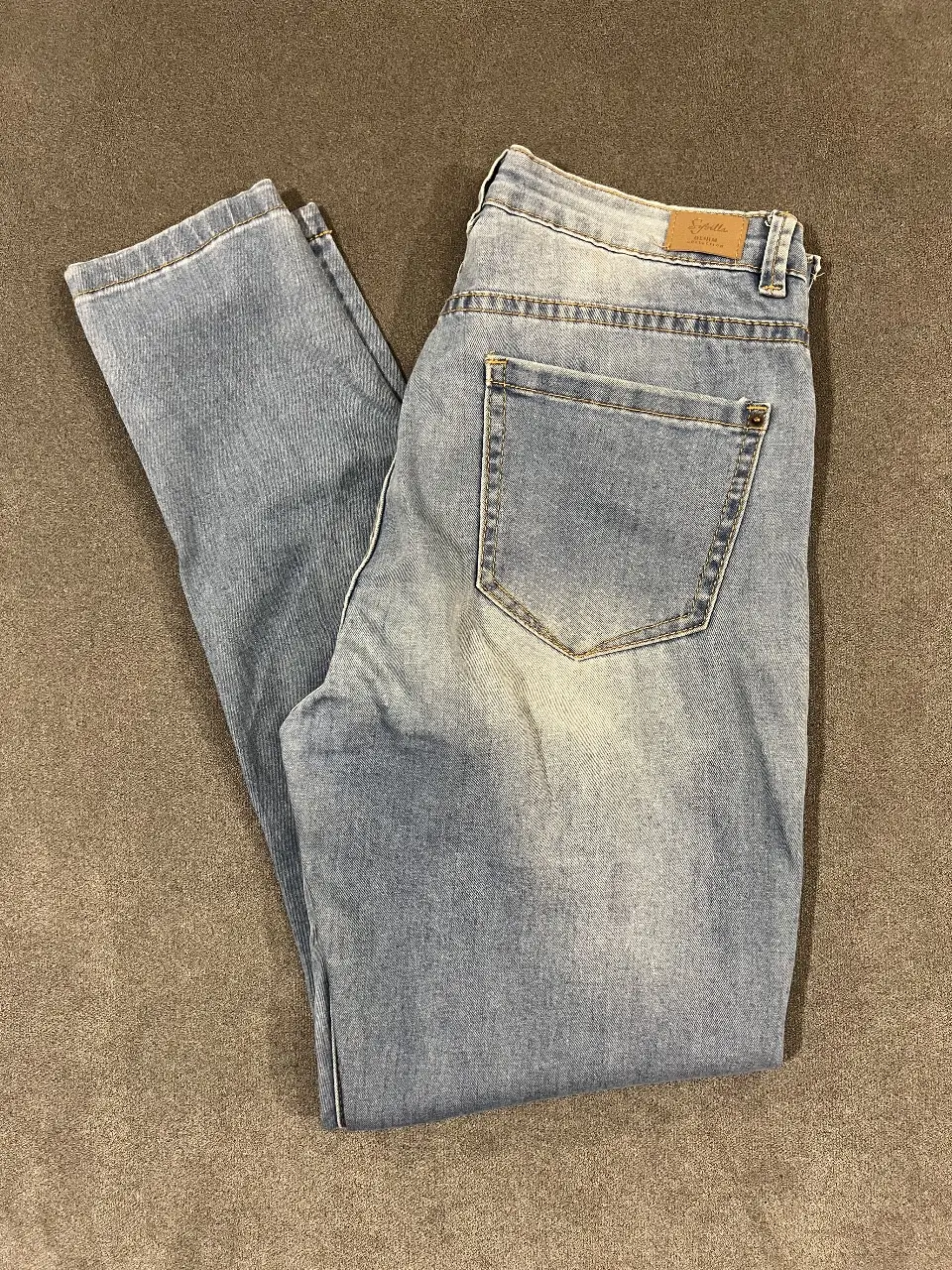 Jeans de mujer, tiro alto, con roturas en las rodillas. Corte chupin, ideal para un look casual y moderno.