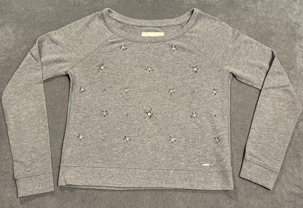 Buzo de cuello redondo gris con apliques de strass. Ideal para un look casual y canchero.