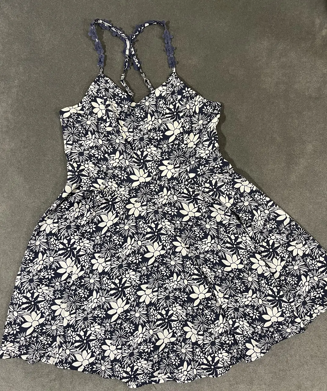 Vestido mini de mujer, con estampado floral en blanco y azul marino. Diseño con tirantes finos y espalda descubierta con ajuste de lazo. Ideal para un look fresco y veraniego.