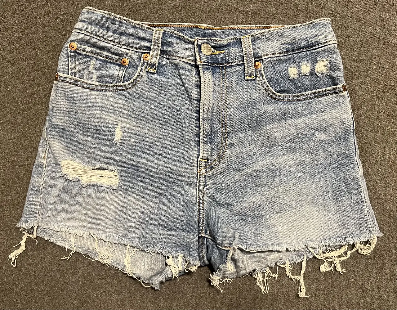 Short de jean de mujer, tiro alto, con detalles de roturas y desflecado en los bordes. Ideal para un look casual y moderno.