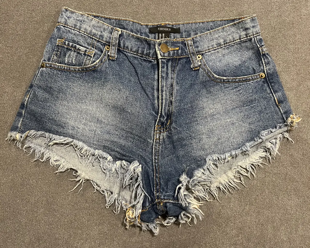 Short de jean de mujer, tiro medio, con detalles desflecados en los bordes. Ideal para un look casual y fresco.