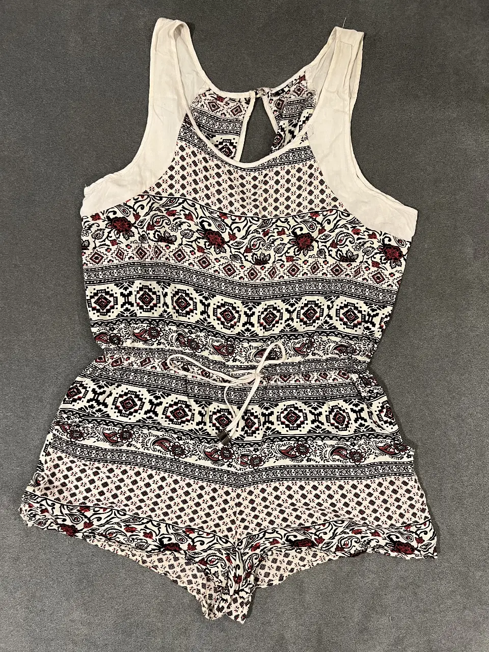 Mono corto de mujer con estampado en blanco, negro y rojo. Tiene un diseño con detalles en la parte superior y un cinturón para ajustar la cintura. Ideal para un look fresco y casual.