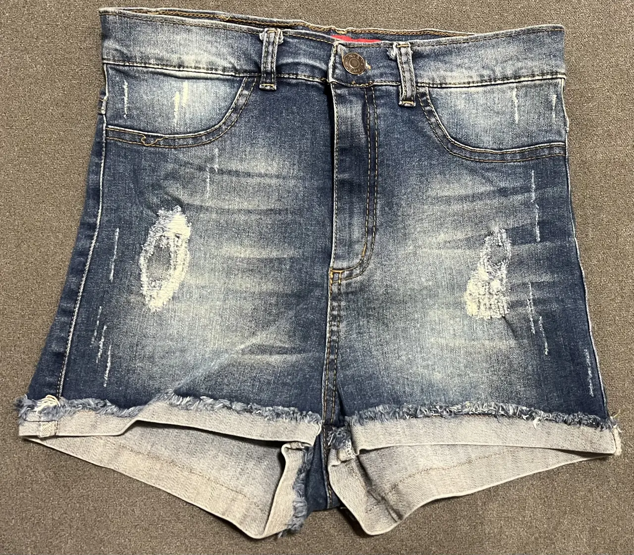 Short de jean de mujer, tiro alto, con detalles rotos y desflecado en el borde. Ideal para un look casual y moderno.