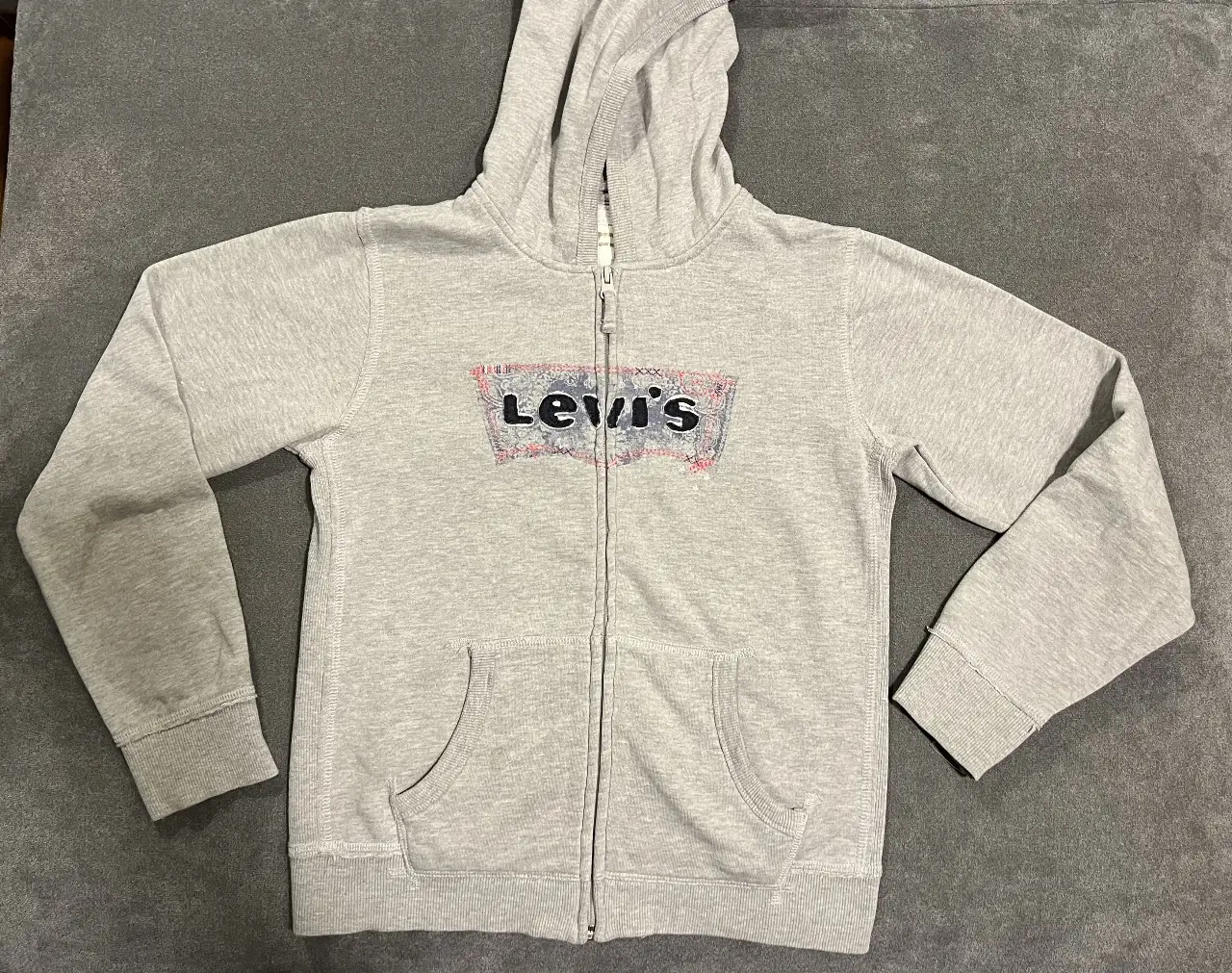 Buzo con cierre de mujer, de la marca Levi's, color gris. Con logo estampado en el frente. Ideal para un look casual y cómodo.