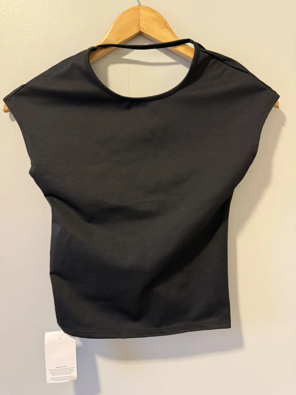 Top negro de mangas cortas y escote redondo. Presenta un detalle de torsión en la parte inferior delantera.