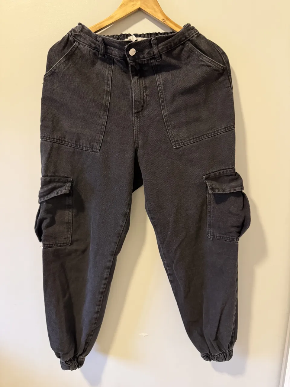 Pantalón de jean cargo negro con bolsillos laterales y elástico en la cintura y tobillos.