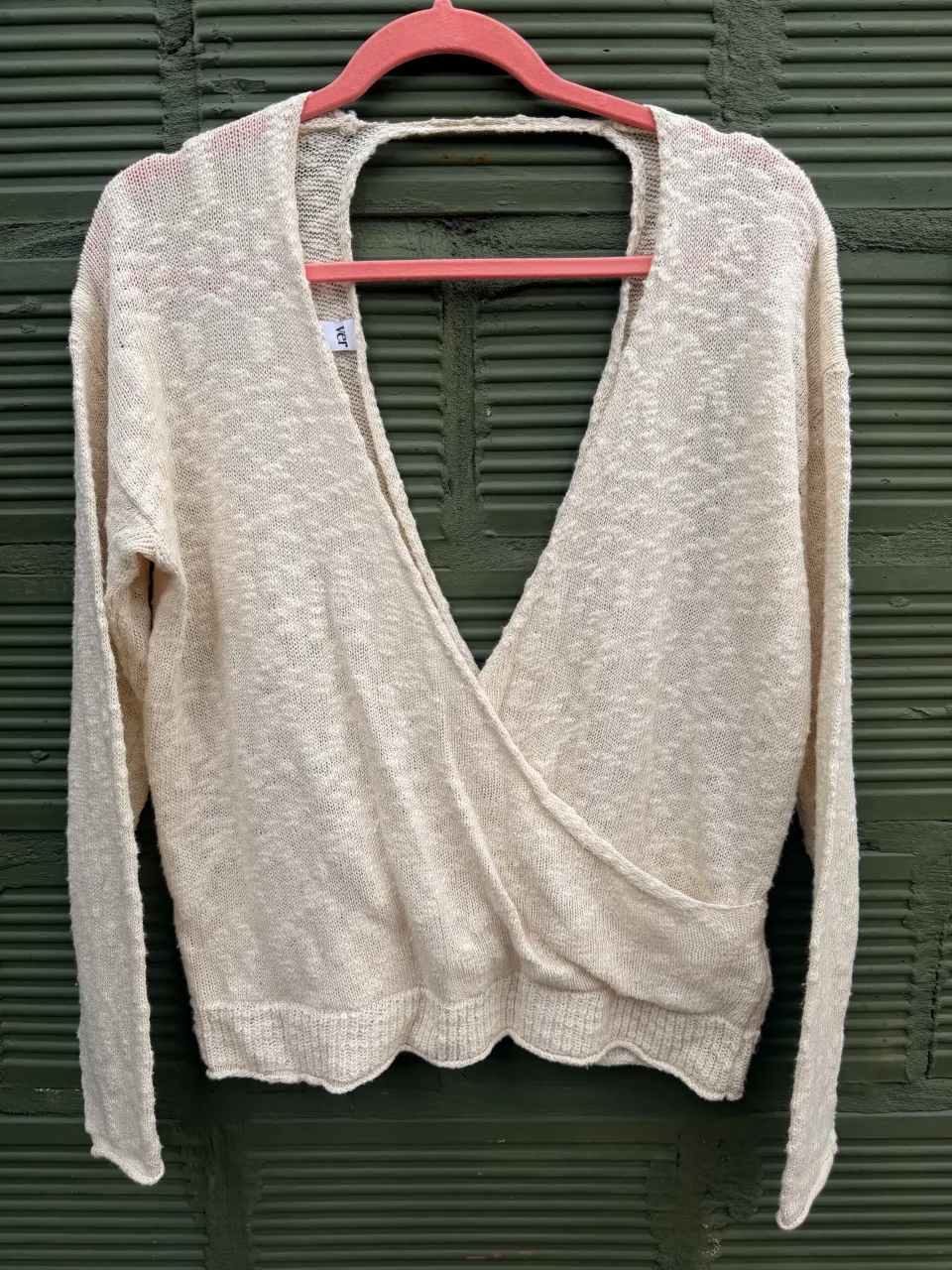 Sweater de tejido liviano color crudo con escote en V profundo cruzado y manga larga. 