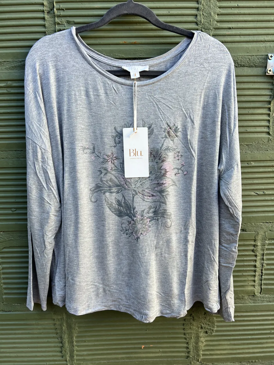 Conjunto de pijama de dos piezas. Remera gris de manga larga con estampa floral en el frente. Pantalón gris con estampa de lunares blancos.