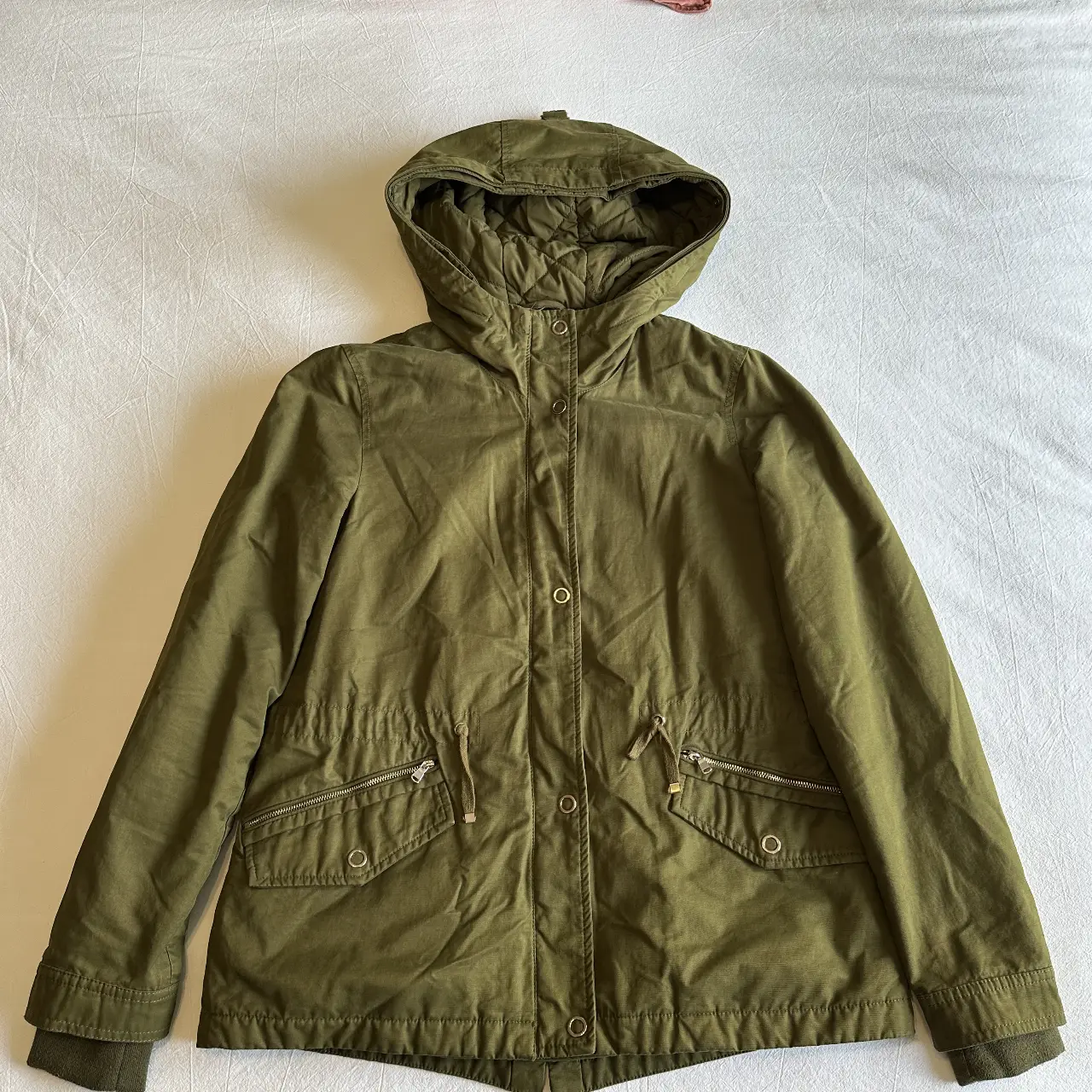 Campera doble desmontable verde militar con capucha, cierre y bolsillos. La parte de adentro se puede sacar y usar por separado. 