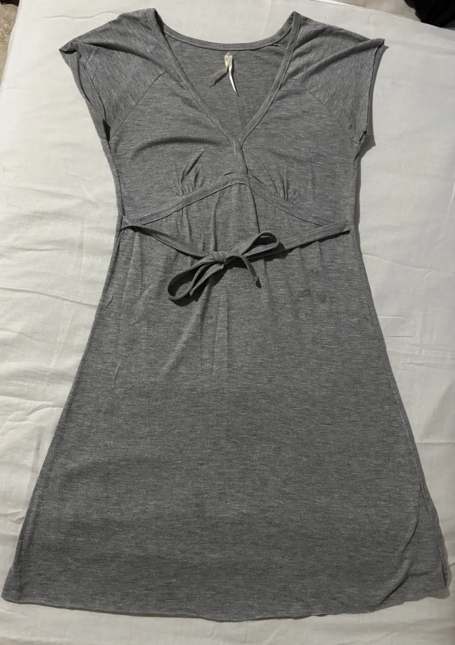 Vestido gris de algodón, con escote en V y lazo en la cintura. Ideal para un look casual y cómodo.
Tiene una pequeña mancha pero en persona es menos visible.