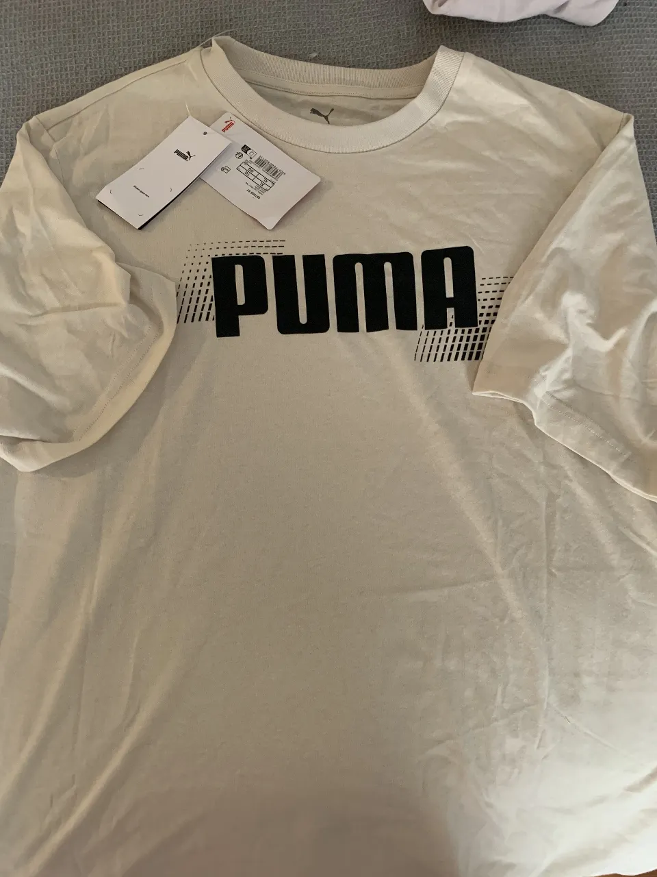 Remera blanca de algodón con estampa PUMA en el frente. Ideal para un look casual y deportivo.