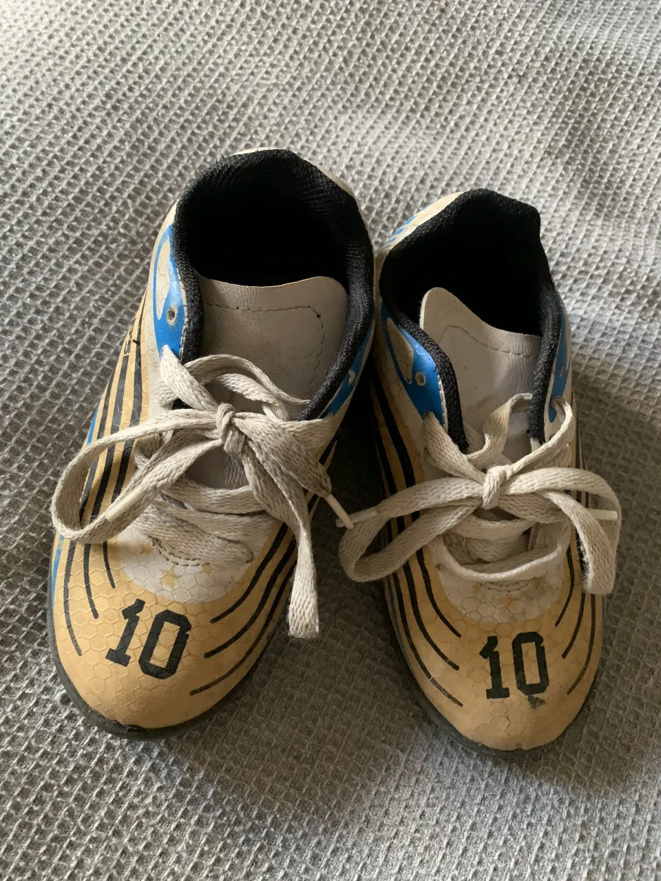 Zapatillas de fútbol para niños, color amarillo con detalles en azul y negro. Número 10 en el frente.
