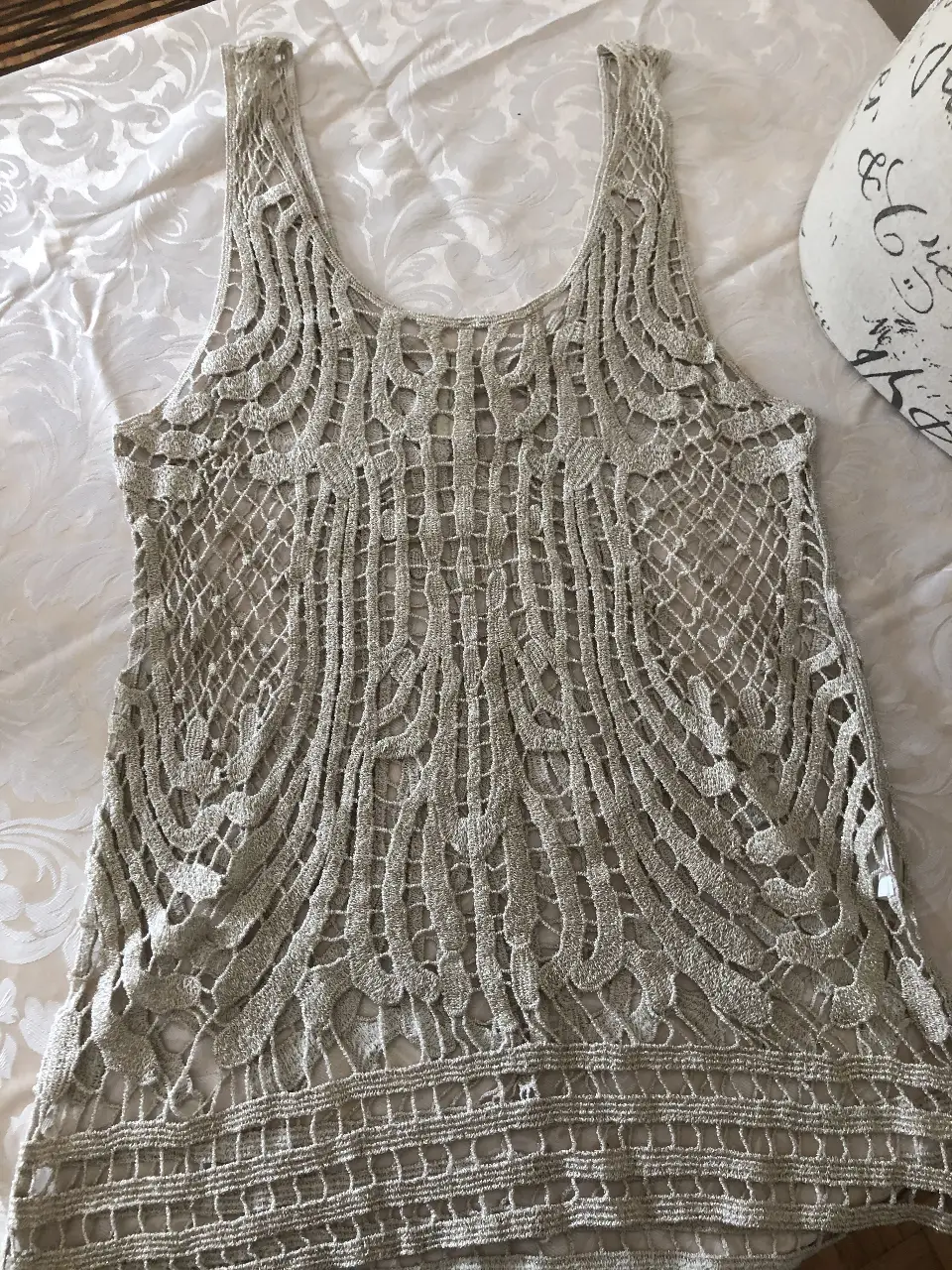 Top tejido de encaje calado en color dorado con brillos, ideal para un look de fiesta. Perfecto para combinar con shorts o polleras en verano.