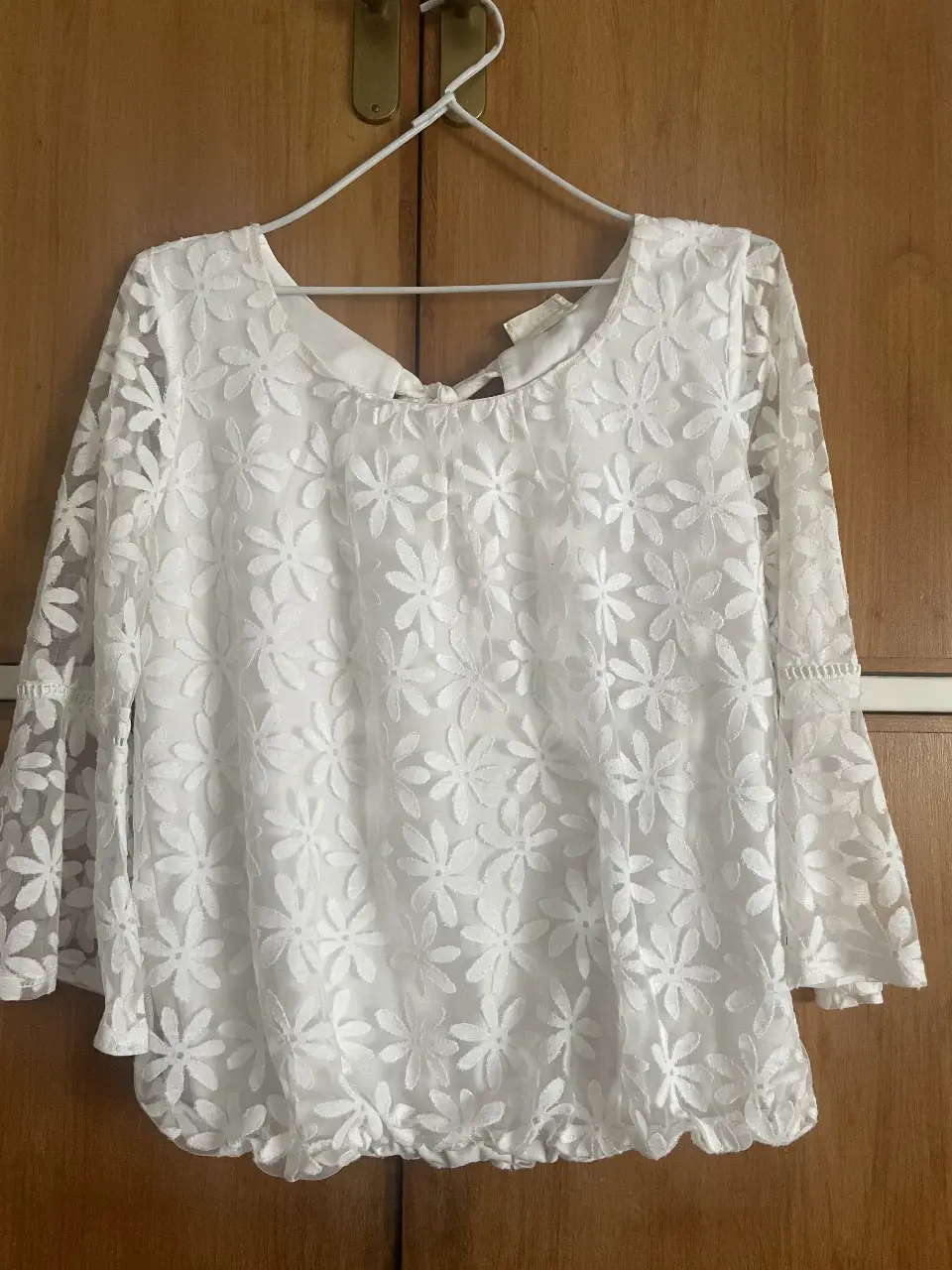 Blusa de encaje floral blanca, manga larga con detalle de volados en los puños y cintura elastizada. Ideal para un look romántico y elegante.