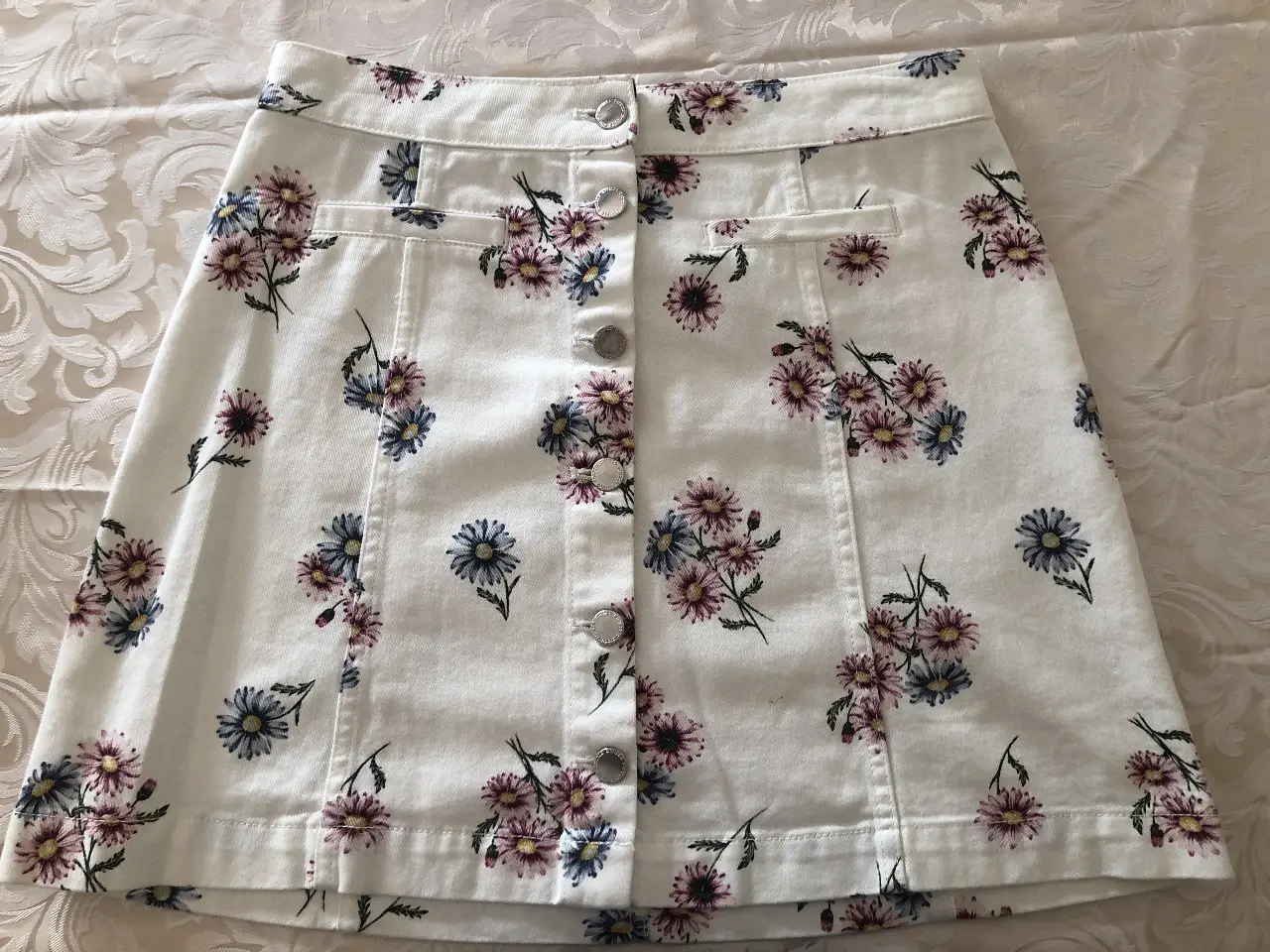 Pollera arriba de la rodilla de jean blanca con botones al frente y con estampado floral. tiene sólo dos usos, está impecable ! IIdeal para el verano. 
