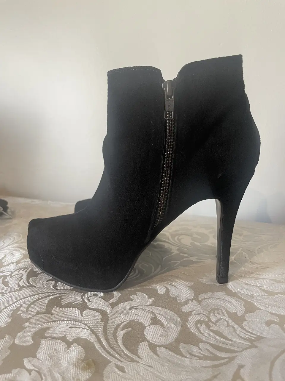 Botines negros de gamuza con taco aguja y cierre lateral. Ideales para un look elegante y sofisticado.