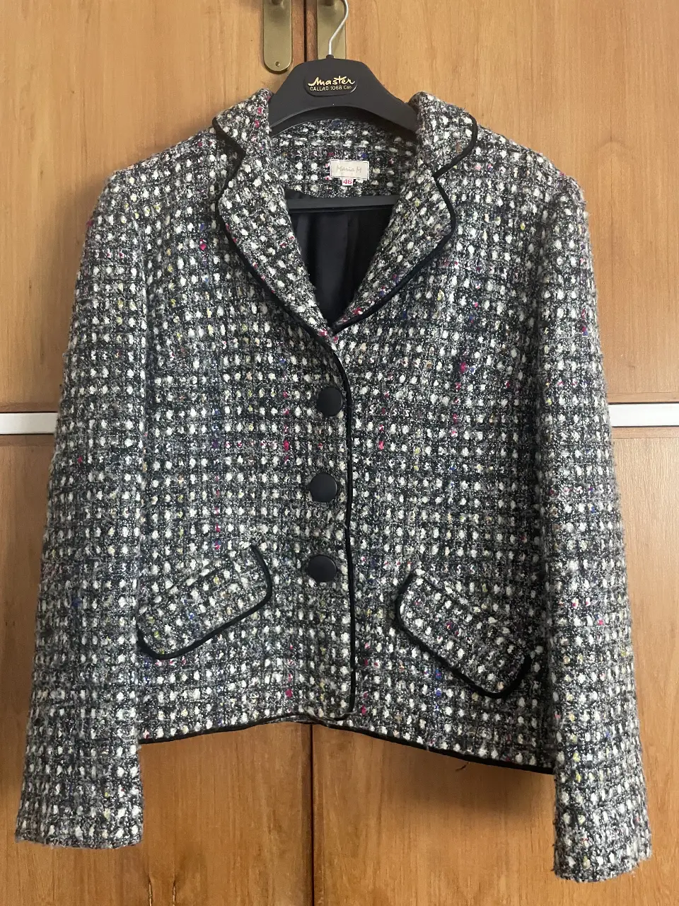 Elegante blazer de tweed en tonos grises y blancos, con detalles en negro. tiene hombreras. Perfecto para un look sofisticado de trabajo o salida.