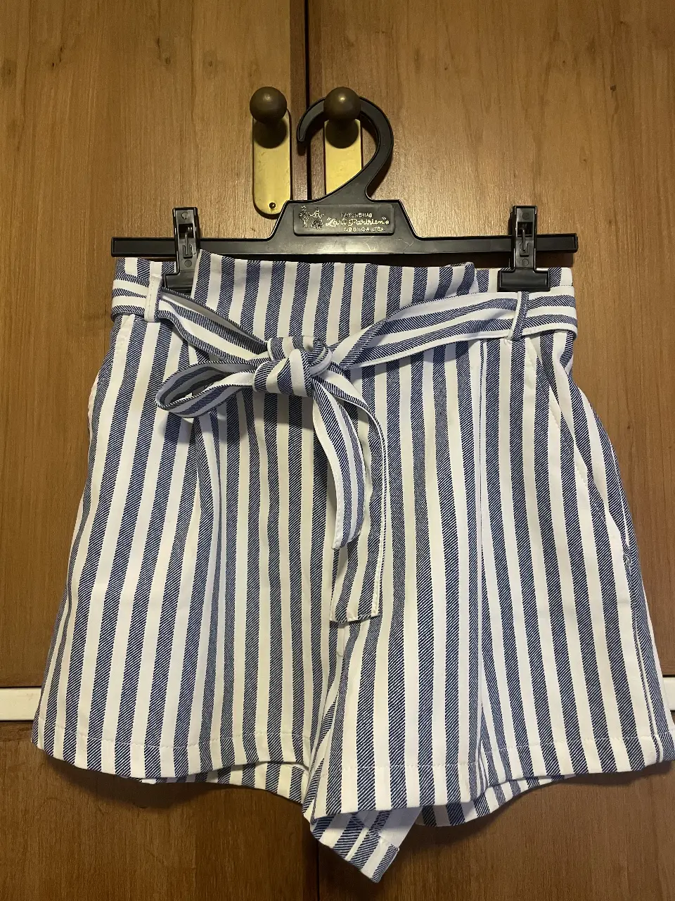 Short de mujer a rayas verticales en blanco y azul, con cintura alta y lazo para atar. marca pull and bear.  Ideal para un look casual y fresco.