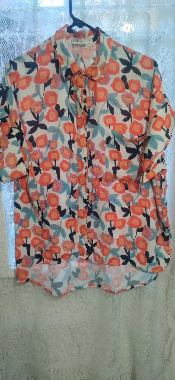 Camisa estampada para mujer, con diseño floral en tonos naranja, blanco y detalles en azul. Corte clásico con cuello y botones, ideal para un look casual y fresco.