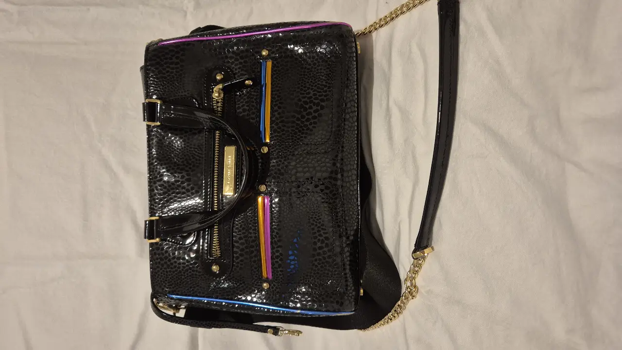 Cartera negra con detalles en charol y detalles multicolores. Diseño elegante y moderno, ideal para complementar cualquier look. Cuenta con correa para llevar al hombro y detalles dorados.