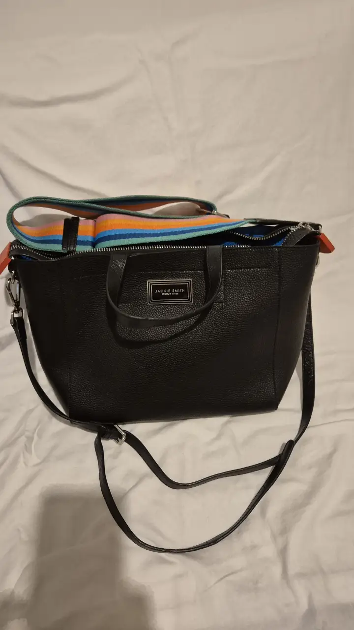 Cartera Jackie Smith negra con correa larga y detalles en colores. Ideal para llevar tus esenciales con estilo.