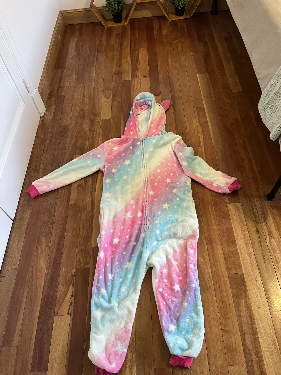 Pijama entero de unicornio para niña, con diseño de estrellas y arcoíris. Incluye capucha con cuerno y orejas.