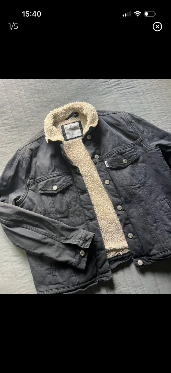 Campera de jean negra con forro interno de corderito color crudo. Cuello con solapa y botones al frente. Dos bolsillos con tapa en el pecho y dos bolsillos laterales.