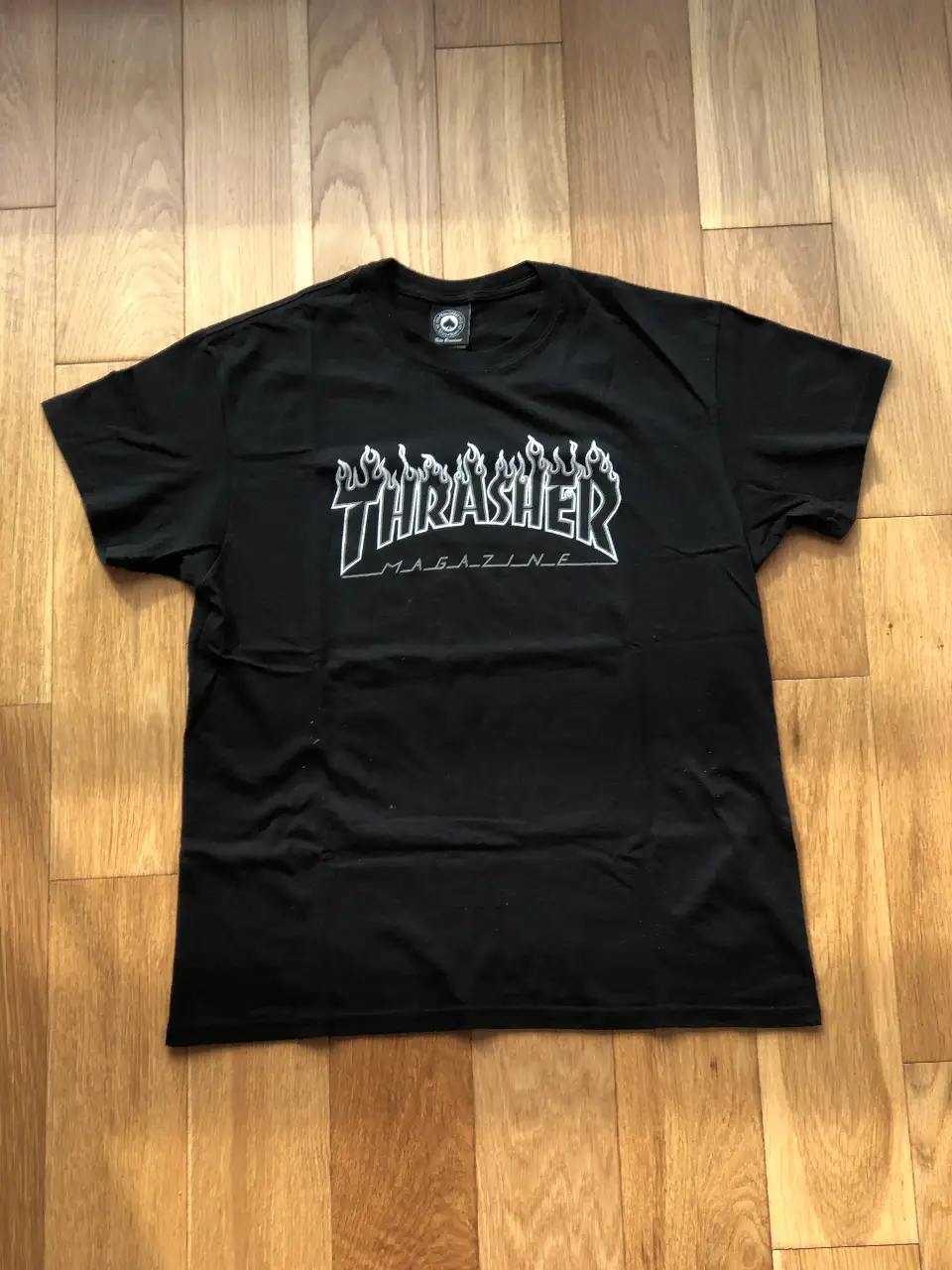 Remera negra de la marca Thrasher, con el logo icónico de la revista estampado en blanco. Ideal para un look skater o casual.