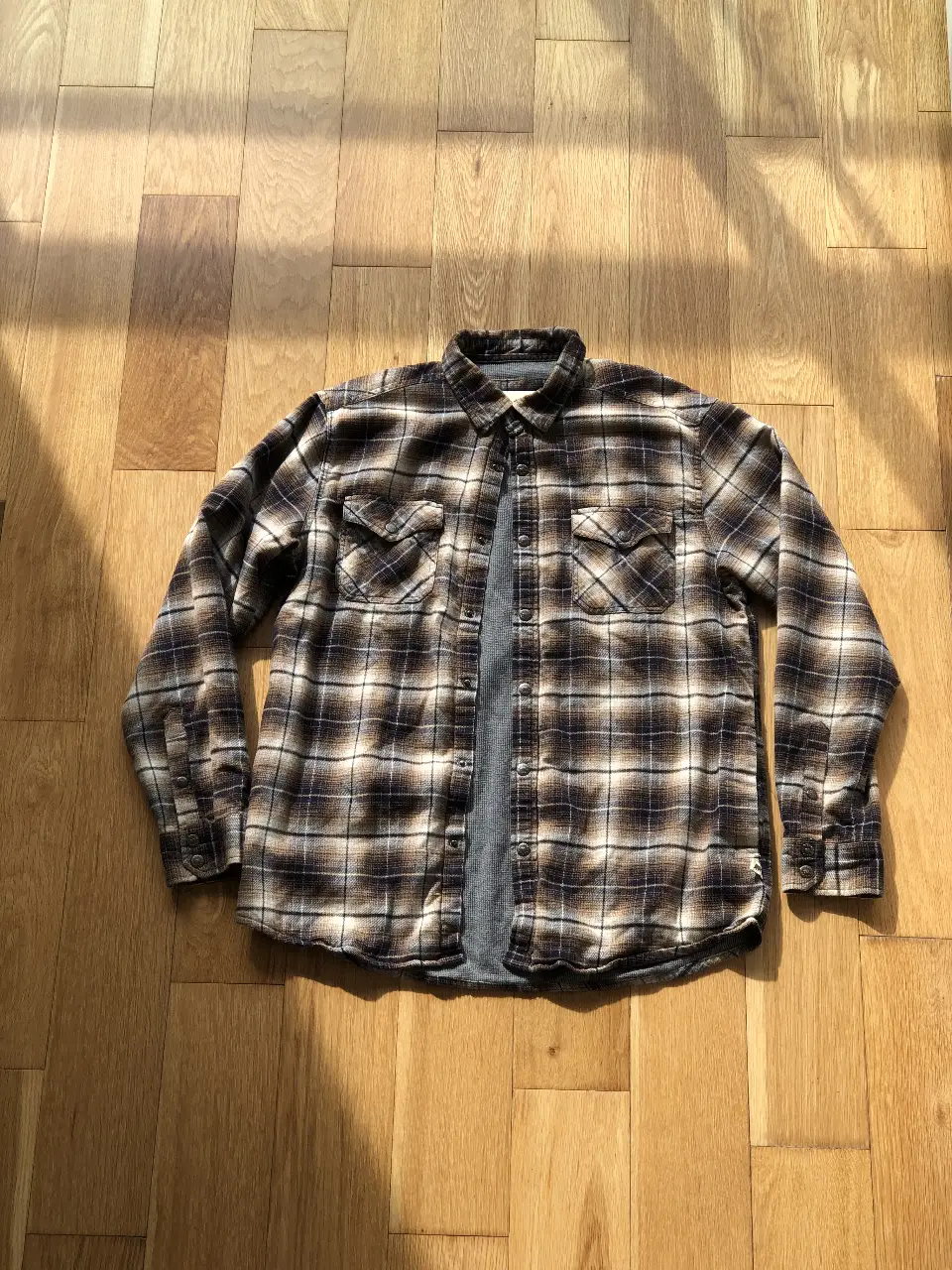 Camisa de leñador a cuadros en tonos marrones y blancos, ideal para un look casual y abrigado. Confeccionada en un tejido suave y resistente, perfecta para el invierno.